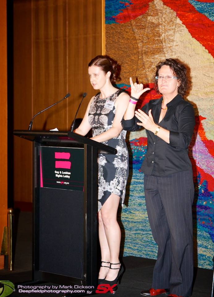 Julie Tait interpreting beside a presenter at a lectern
