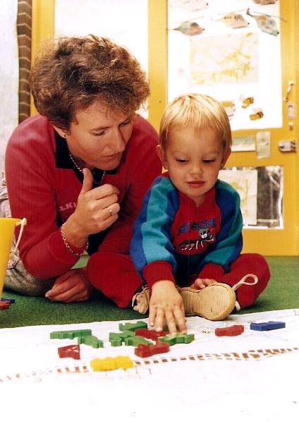 Julie working beside a young Deaf child during a classroom activity