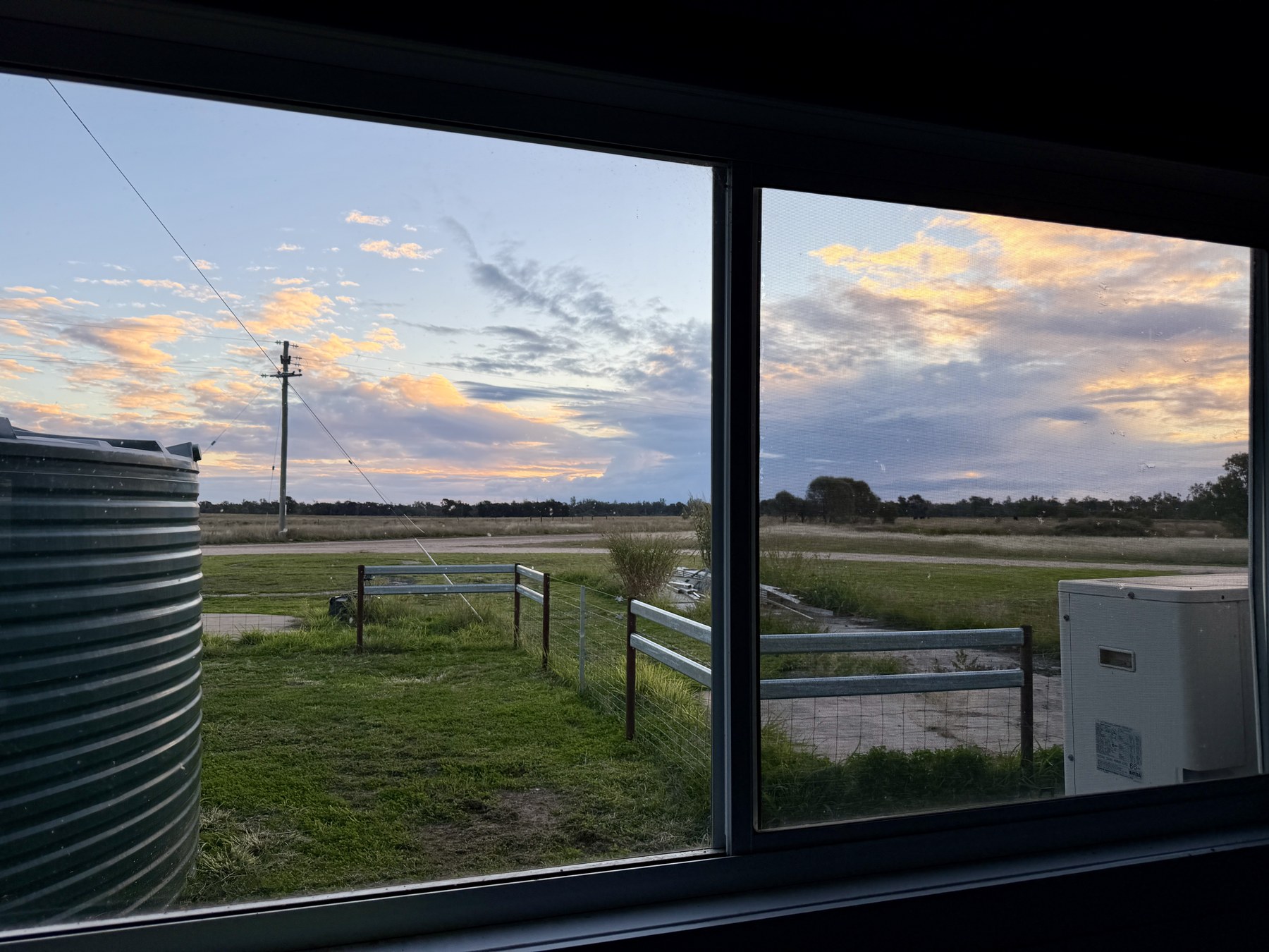 Evening sky and paddocks seen through a window near Condamine