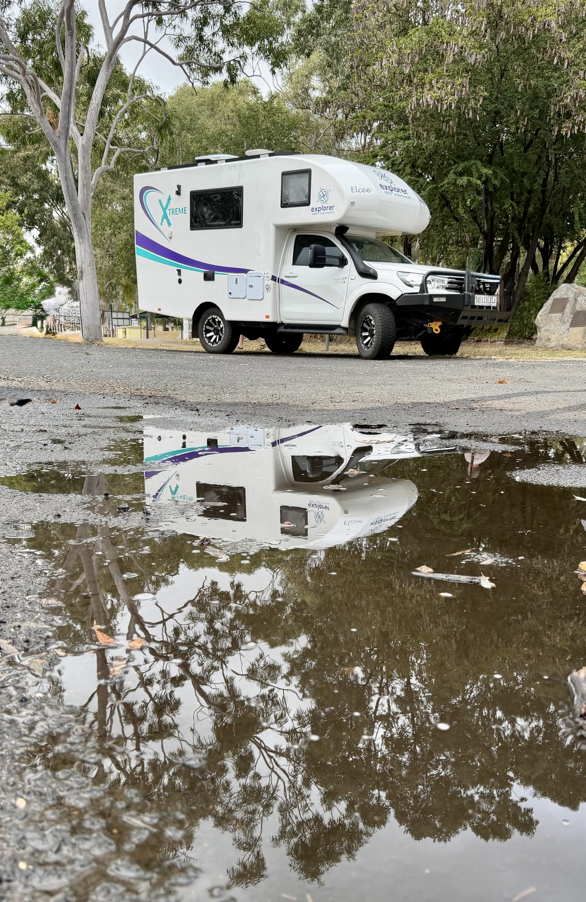 Elcee parked outside the Springsure Visitor Information Centre with a reflection in a puddle