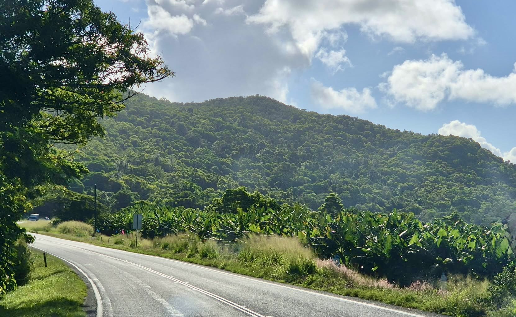 Road climbing towards green hills under dramatic clouds