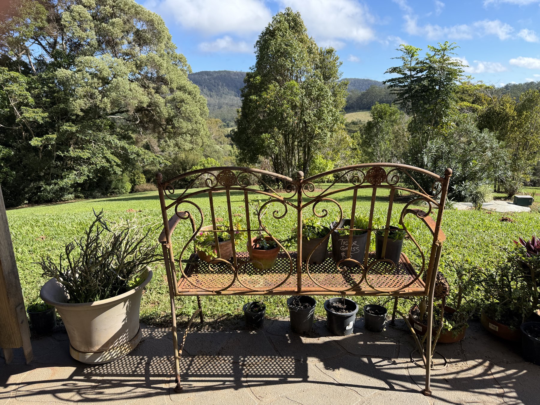 Garden bench and potted plants looking out across green Tablelands hills