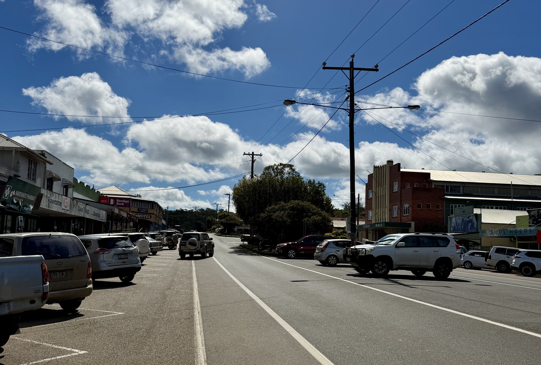 Main street of Ravenshoe with shops, cars and clouds overhead