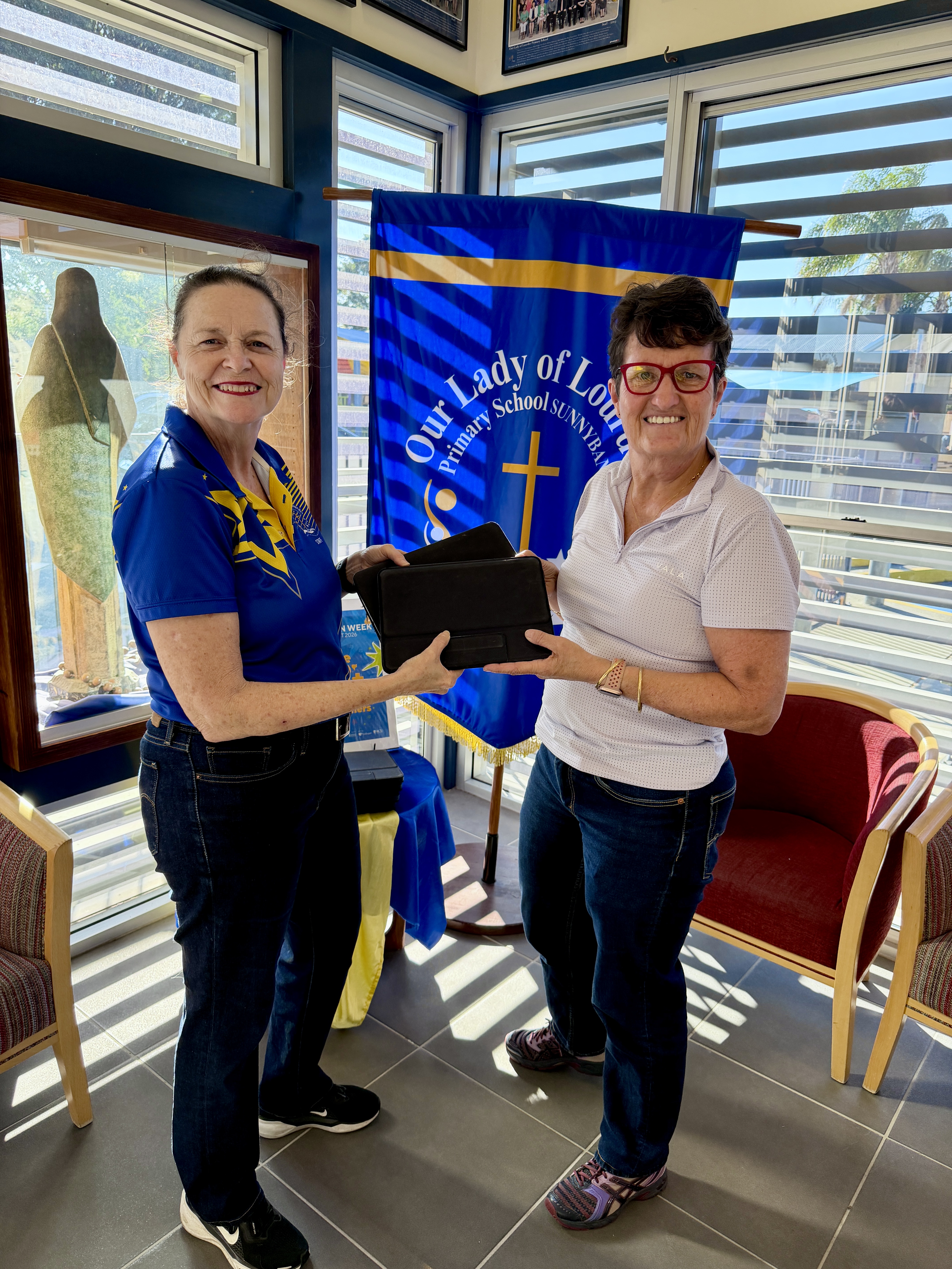 Julie and Julie holding a donated iPad at Our Lady of Lourdes Primary School