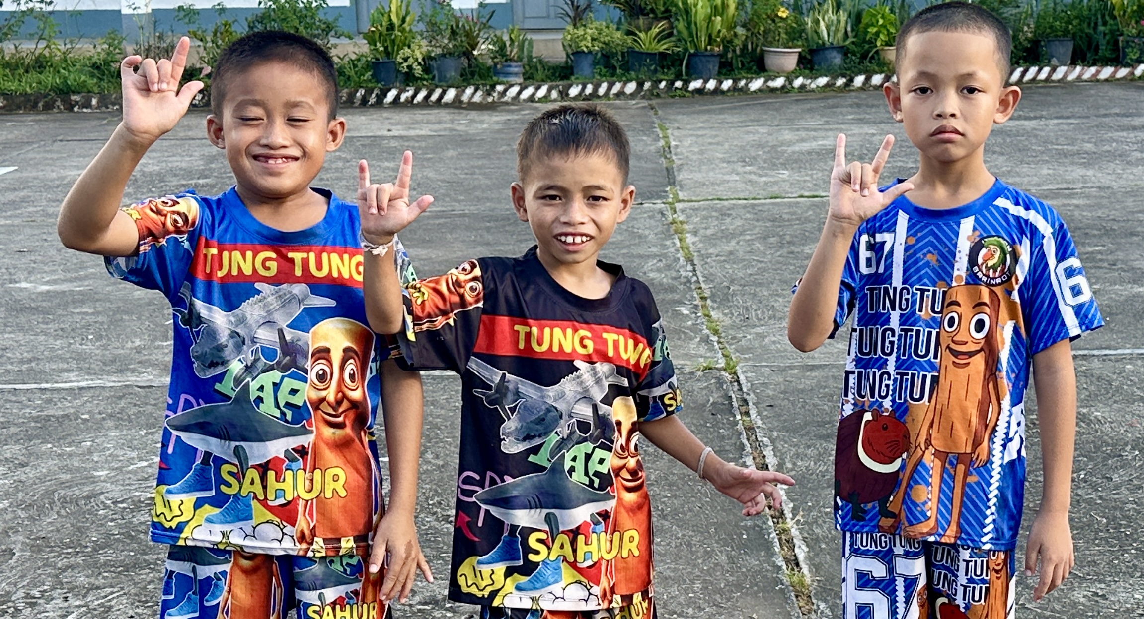 Three young students signing in the Luang Prabang School for the Deaf courtyard
