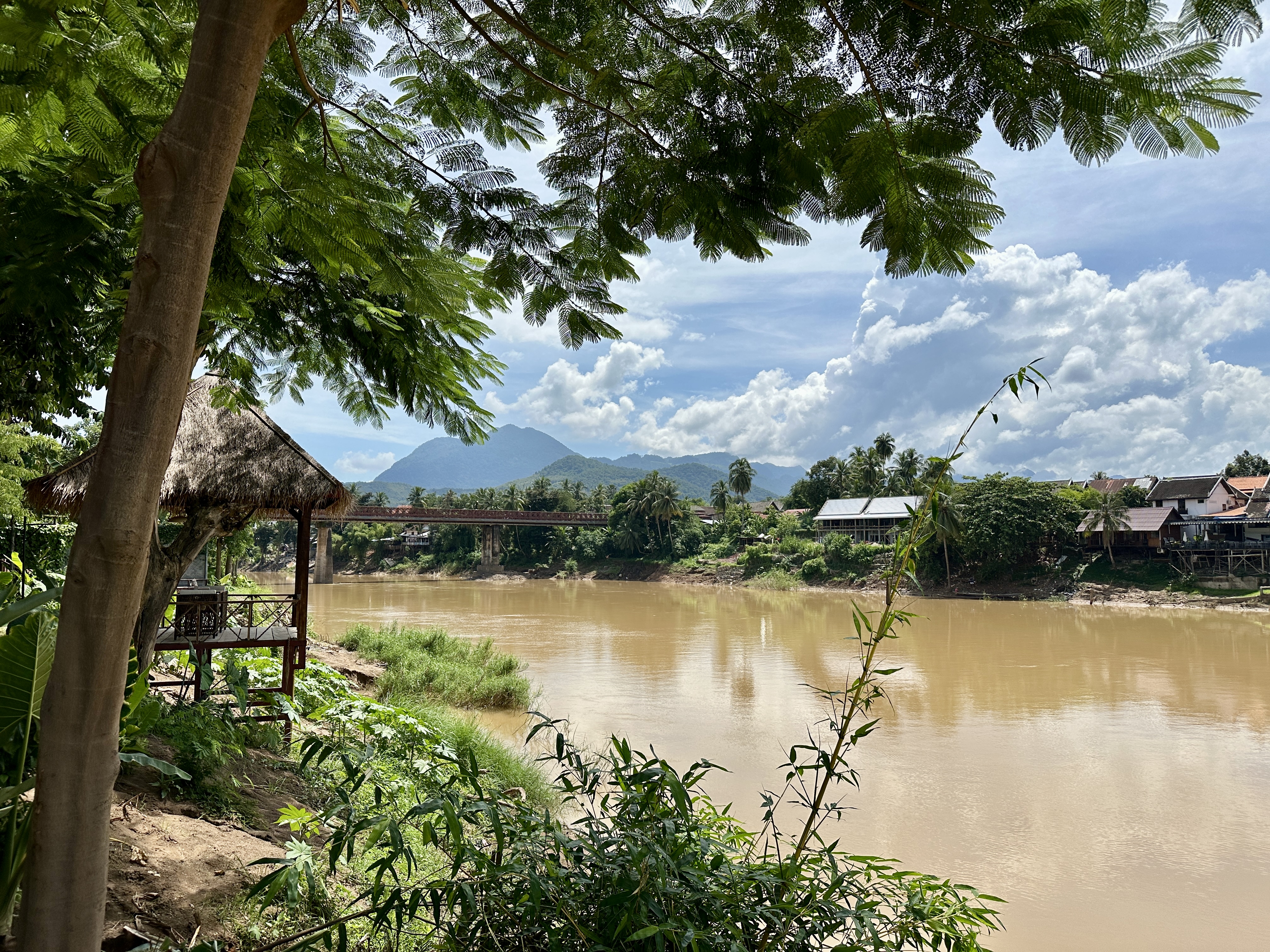 Luang Prabang river, bridge and mountains beneath leafy trees